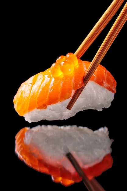 Salmon sushi nigiri in chopsticks isolated