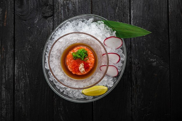 Salmon tartare and caviar On the ice on a dark table