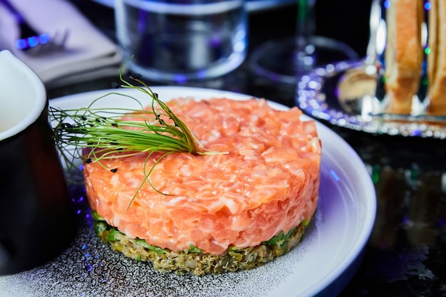 Salmon tartare with avocado on a white plate in a restaurant