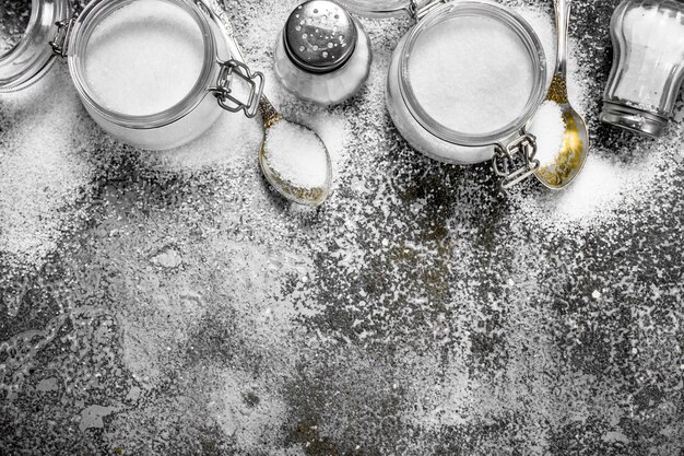 Salt in jars and spoons. On rustic table.