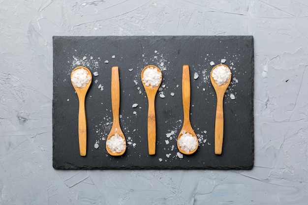 Salt on many wooden spoon on wood background Spoons with different salt