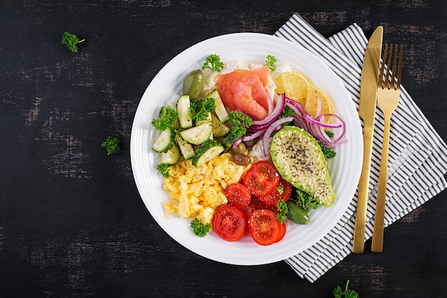 Salt salmon salad with tomatoes, cucumbers, scrambled eggs and avocado. Ketogenic diet breakfast. Keto lunch. Top view, overhead