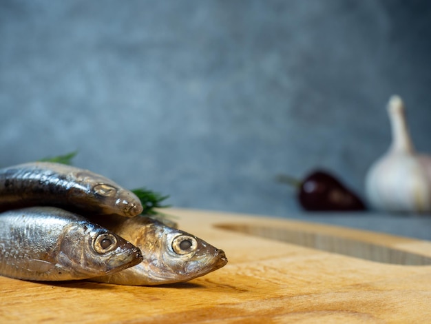 Salted fish on a cutting board Three sprats and garlic on the table