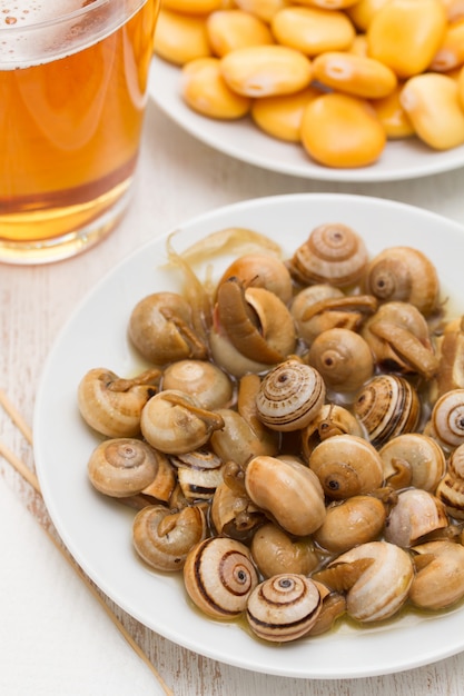 Salted lupins on white plate and snails with glass of beer