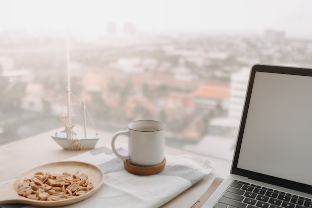 Photo salted peanuts black coffee and laptop on the desk