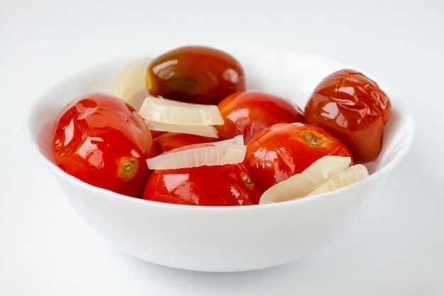 Salted pickled tomatoes with onions in a white plate