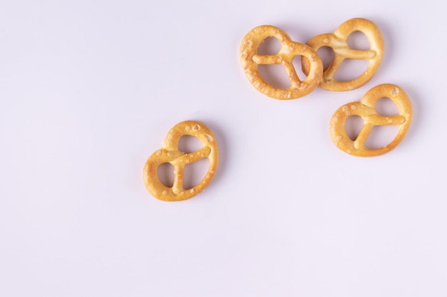 Salted pretzels are scattered on a white background, space for text