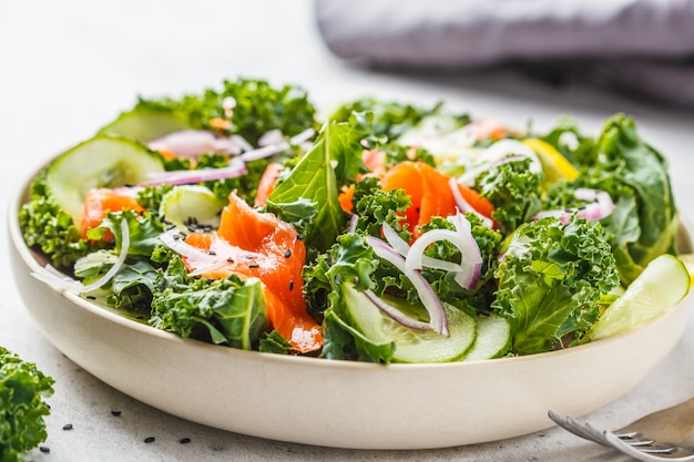 Salted salmon (trout) and Kale salad in a white plate on a white background.