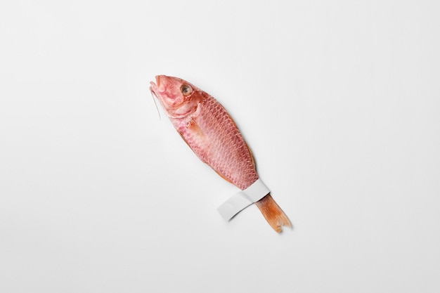 Salted sundried red mullet with paper label on tail on white surface