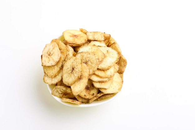 Salty banana chips in bowl on white background