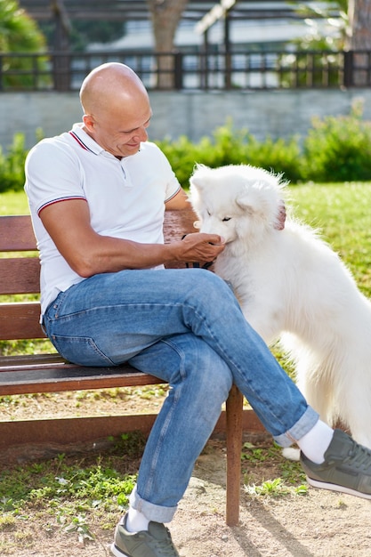 Samoyed dog with her man owner at the park playing together