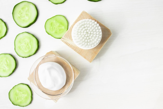 A sample of a moisturizing cosmetic product and a piece of green cucumber on wooden background