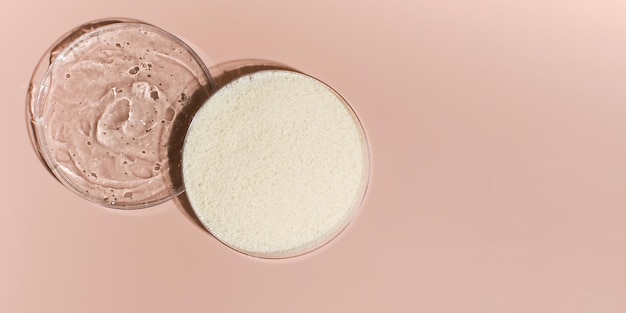 Samples of collagen powder and hyaluronic acid in Petri dishes on a pink background closeup view from above Copy space