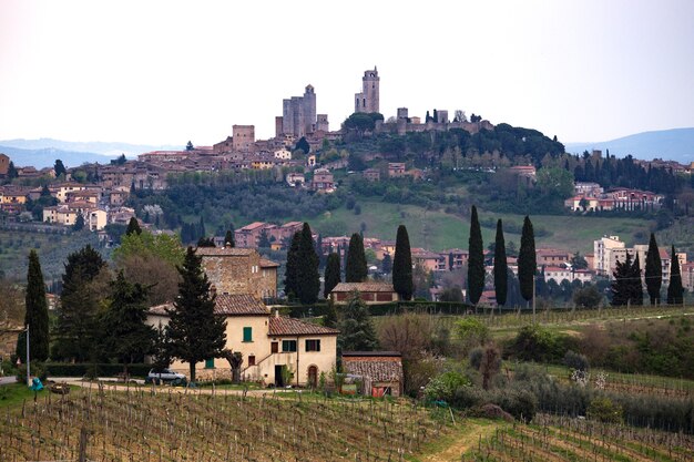 Photo san gimignano. typical tuscan landscape - a view of a villa on a hill, a cypress alley and a valley with vineyards, province of siena. tuscany, italy