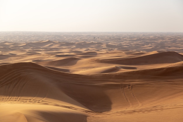 Sand dunes of the desert with traces of car wheels