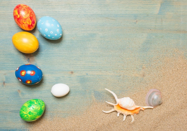 Sand and easter eggs on blue planked wood Festive background with copy space Top view