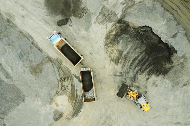 Sand loaders are shoveling rocks into dump trucks