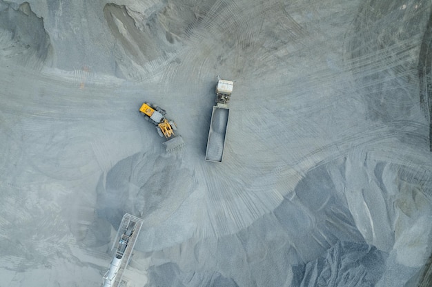 Sand loaders are shoveling rocks into dump trucks