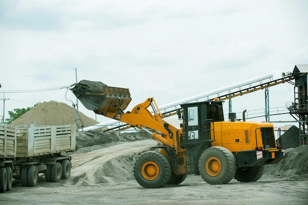 Sand loaders are shoveling rocks into dump trucks