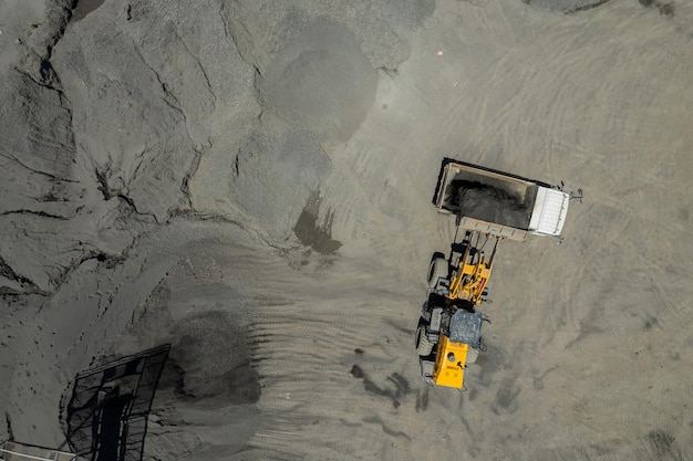 Sand loaders are shoveling rocks into dump trucks