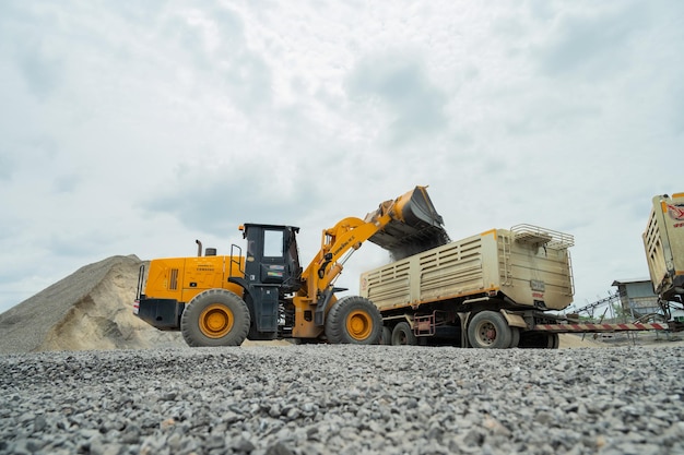 Sand loaders are shoveling rocks into dump trucks