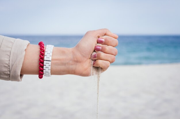 Sand pours from a female hand on the beach