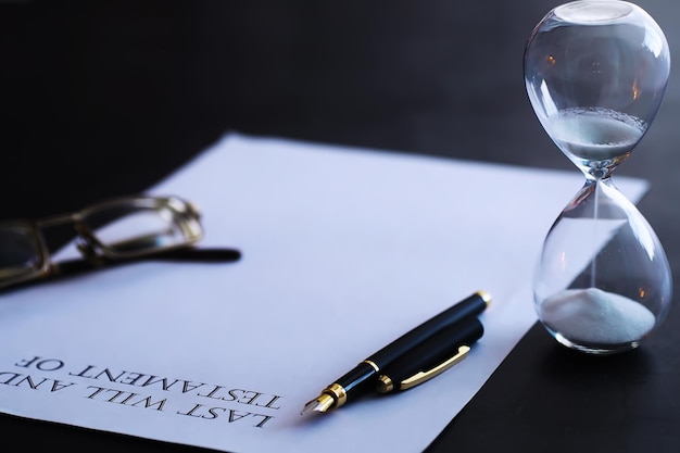 Sand running through the bulbs of an hourglass measuring the passing time in a countdown to a deadline, on a dark table background with copy space.