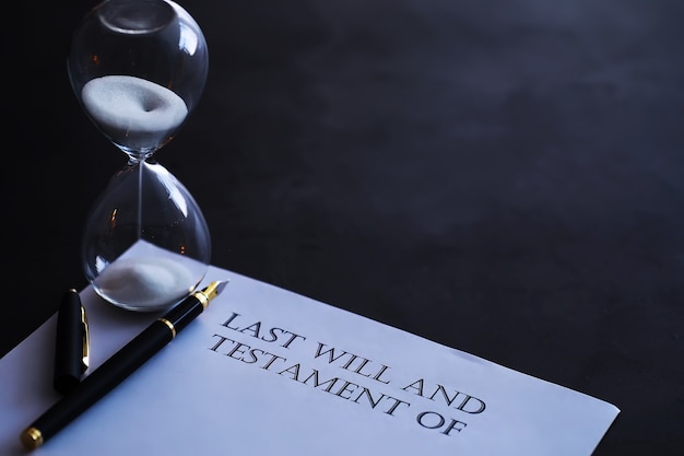 Sand running through the bulbs of an hourglass measuring the passing time in a countdown to a deadline, on a dark table background with copy space.