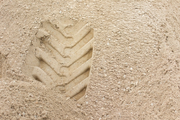 Sand texture with visible grains and wheel imprint into surface. Photo with copy blank space.