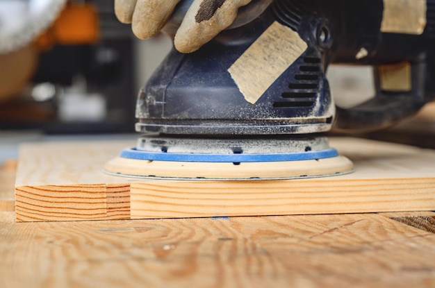 Sanding a wooden board with a handheld electric sander