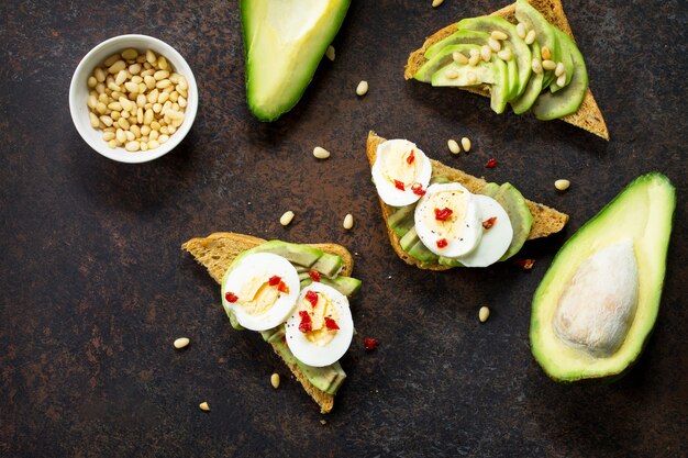 Sandwich avocado with fresh sliced avocado egg poached and spices on a dark slate or stone surface Copy space Flat lay top view