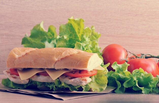 Photo sandwich baguette with chicken breast, cheese and tomatoes