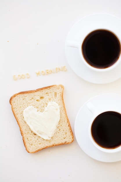 Sandwich for breakfast in form of heart with cheese good morning sign and two coffee cups