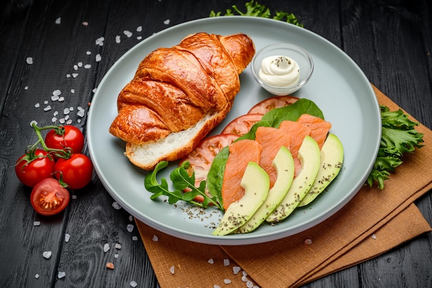 Sandwich Croissant with salmon cream cheese avocado and vegetables Serving in a cafe Photo for the restaurant menu