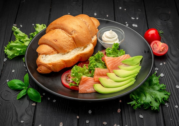 Sandwich Croissant with salmon cream cheese and vegetables Serving in a cafe Photo for the restaurant menu