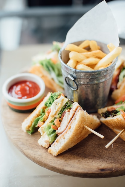 Sandwich, fries and sauce on wooden board