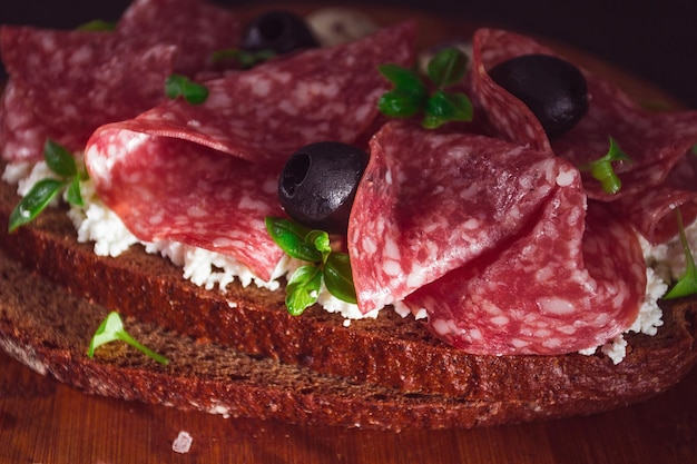 Sandwich grain bread with cream cheese and salami black olives microgreens top view closeup no people Breakfast