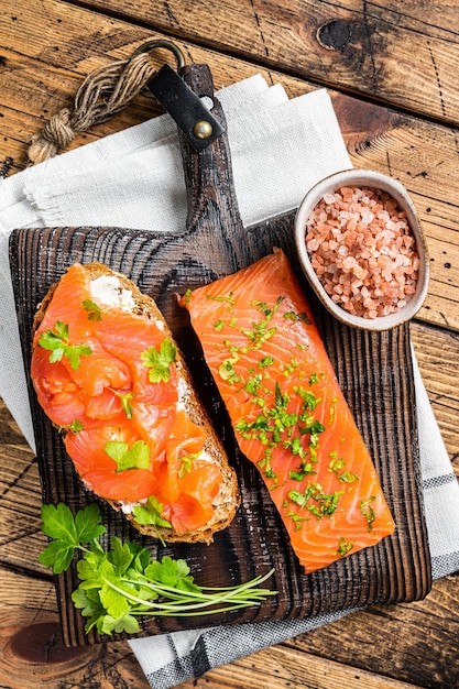 Sandwich toast with Salted salmon fillet herbs on a wooden board Wooden background Top view