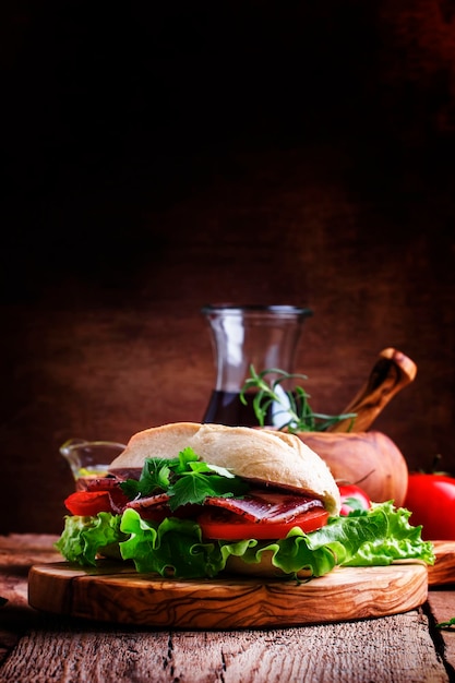 Sandwich in wheat bun with smoked ham tomatoes and lettuce selective focus