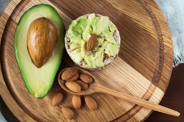 Sandwich with avocado and almonds on a wooden brown background