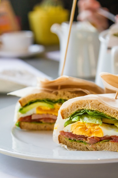 Sandwich with egg, ham, avocado in restaurant