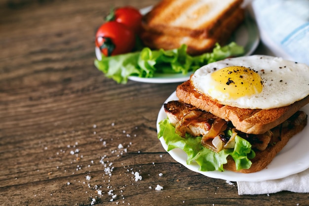 Sandwich with eggs chicken cucumber and lettuce on a wooden background Selective focus copy space