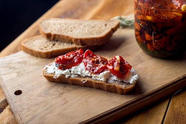 Sandwich with goat cheese sundried tomatoes and thyme served on the Board at a bright wooden surface