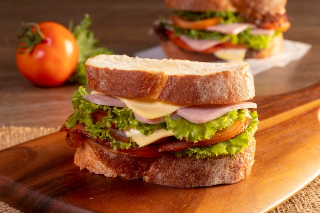 Sandwich with ham and vegetables on a wooden table