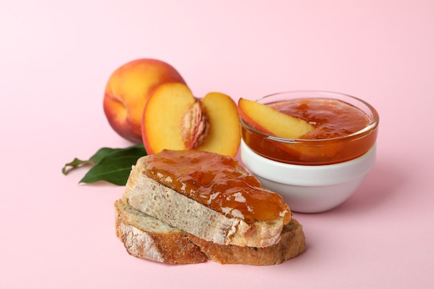 Sandwich with peach jam and ingredients on pink background