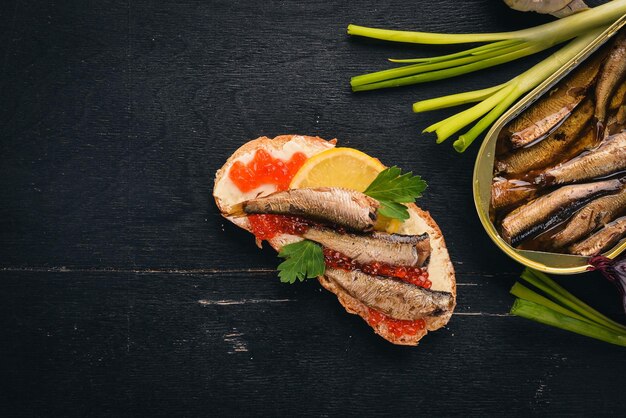 Sandwich with sprats and caviar onion on a wooden background Top view Copy space