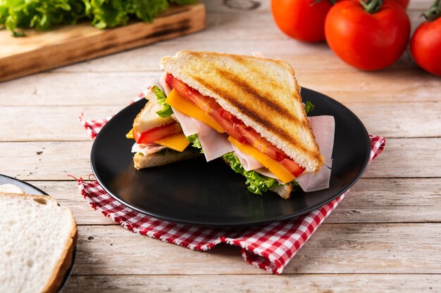 Sandwich with tomato,lettuce,ham and cheese on wooden table