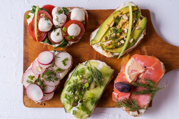 Sandwiches or tapas with bread , cream cheese, vegetable and tasty toppings.