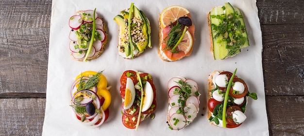 Sandwiches or tapas with vegetables and salmon, on a plate, over wooden background.Flat lay.