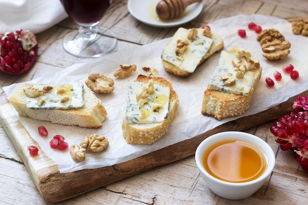 Sandwiches with blue cheese, pomegranate, honey and nuts served with red wine. Rustic style.